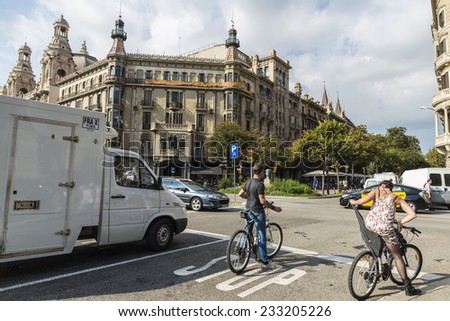 Barcelona, Spain - October 29, 2014: Cyclists stopped at a traffic light with heavy traffic around the city center. In the background, classical buildings of Rambla de Catalunya.