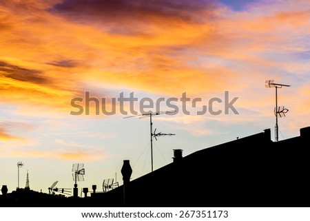 Silhouettes of antennas backlit at sunset with colorful sky clouds