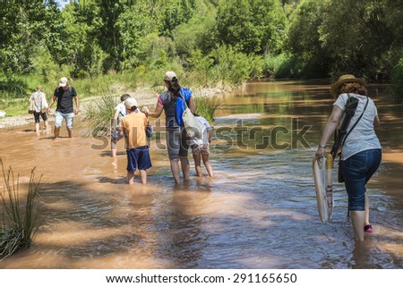 Montanejos, Spain - May 31, 2015: Family crossing a river full of stones with care and teetering