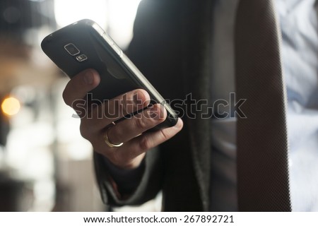 Businessman in suit, jacket,shirt, tie, using his smart phone