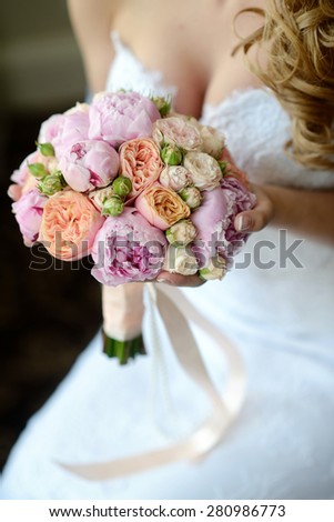 Woman with flowers in hands. Close-up bouquet in arms. Beautiful sexy model girl in a white wedding dress. Beauty bride without groom. Female portrait. Cute lady indoors