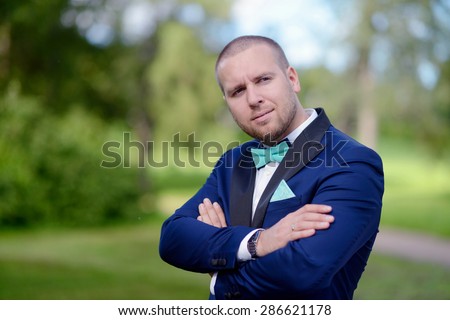 Beauty groom in suit on the nature. Male portrait in the park. Beautiful model boy in colorful wedding clothes. Man is posing. Handsome guy outdoors