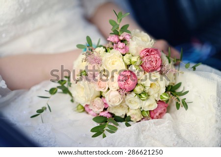 Beautiful bride is holding a wedding colorful bouquet. Beauty of colored flowers. Close-up bunch of florets. Bridal accessories. Female decoration for girl. Details for marriage and for married couple