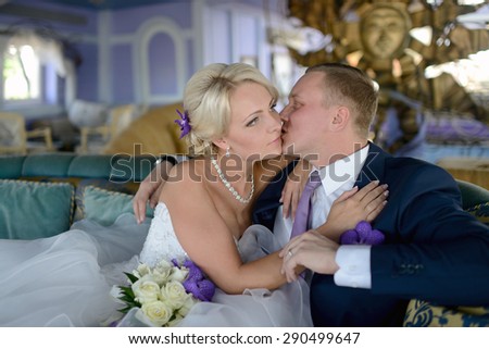 Wedding couple indoors is hugging each other. Beautiful model girl in white dress. Man in suit. Beauty bride with groom. Female and male portrait. Woman with lace veil. Cute lady and handsome guy