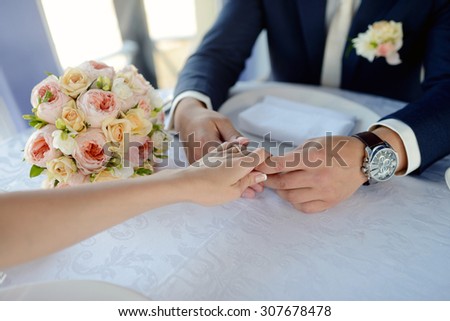 Wedding couple is holding hands. Beauty bride with groom. Beautiful model girl in white dress. Man in suit. Female and male portrait. Woman with lace veil. Cute lady and guy indoors