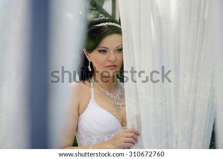Beauty bride in bridal gown indoors. Beautiful model girl in a white wedding dress. Female portrait of cute lady. Woman with hairstyle