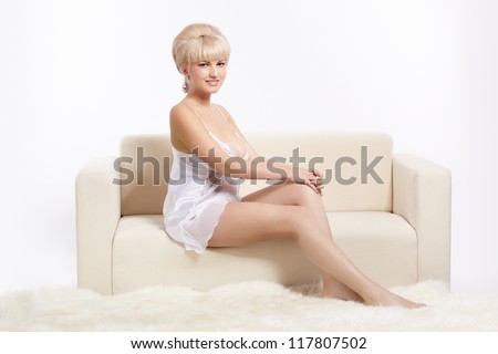 full-length portrait of beautiful young blonde woman in lingerie on white coach