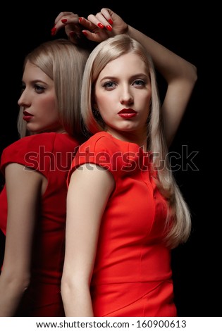 portrait of young beautiful long-haired blonde woman in red dress posing at mirror