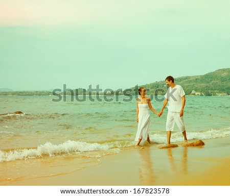 Colorized vintage old film outdoor portrait of young romantic couple in white cotton clothes on beach of Phuket island, Thailand