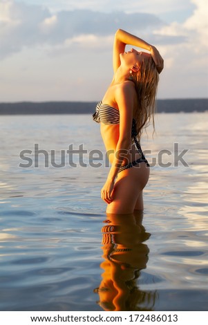 full-length portrait of young beautiful tanned blonde woman in sea