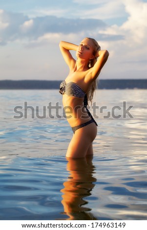 full-length portrait of young beautiful tanned blonde woman posing in sea