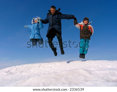 Happy family jumping over snow under blue sky