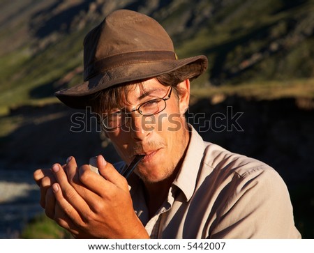 man in hat is smoking tobacco-pipe