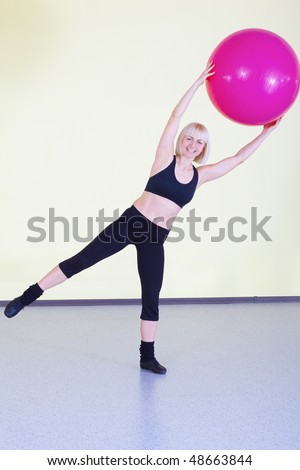 indoor portrait of woman training in gym with swiss ball