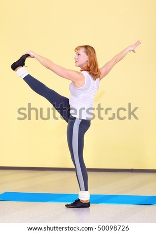 indoor portrait of woman training in gym on fitness carpet