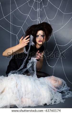 portrait of girl with spider bodyart of face zone and her victim boy in cocoon