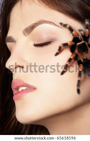 close-up portrait of girl with brachypelma smithi spider creeping over her face