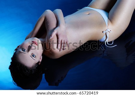 portrait of topless brunette girl laying on blue water floor