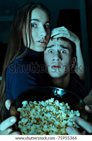 Young couple watching scary movie on tv at Halloween