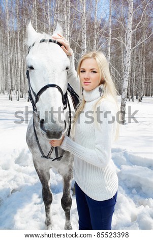 outdoor portrait of beautiful blonde girl with pale horse in sunny winter forest