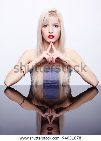 portrait of young beautiful long-haired blonde woman with manicured fingers sitting at mirror table in bracelet and ring