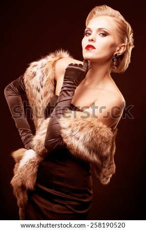 Young blonde woman in black dress and lynx fur with long gloves on dark background toned in marsala color