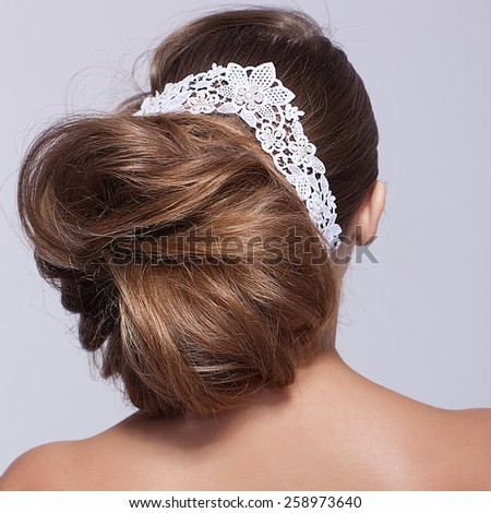 Portrait of beautiful young woman on gray background with lacy white ribbon in hairs from behind