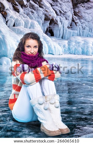 Young woman sitting on ice of siberian Baikal Lake in winter
