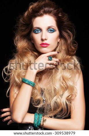 Portrait of young beautiful woman with curly shaggy hair style and blue eyes make-up on black background