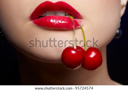 close-up portrait of beautiful girl\'s lower part of face with two red cherries in mouth