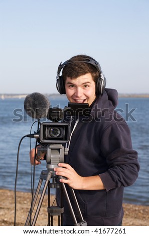 Young man grinning as he films you