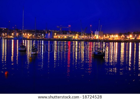 busy dock in Plymouth during the evening with the the reflex of lights afloat