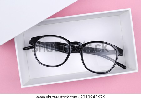 Optical glasses in a stylish black frame are in a white gift box on a pink background.The concept of discounts,promotions, sales in optics stores, repair of glasses,glasses as a gift.Copyspace Сток-фото © 