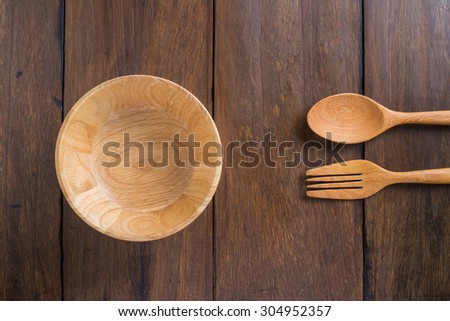 Top view of spoons, forks, wooden bowl on wood table background