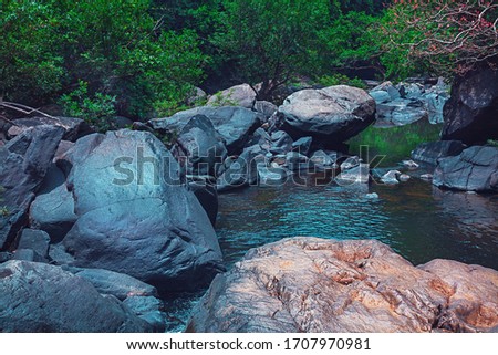 Strong flood of water rocks below.Crystal clear water, huge stones with a beautiful vegetation around. At the end forming a strong current and later a calm lake with clean transparent in India