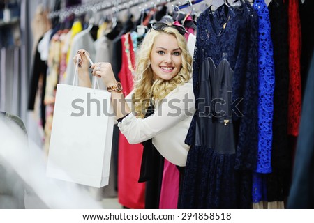 beautiful blonde girl chooses clothes. Girl holding shopping bags.