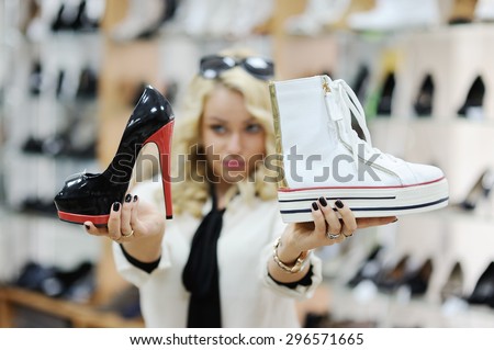 beautiful girl chooses shoes. The girl chooses between sporty and classic style shoes