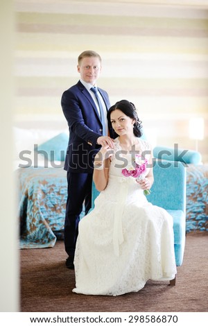the bride and groom in the interior. Bride gently holding the hand of the groom