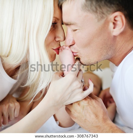 parents kiss the little baby\'s legs