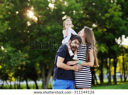 young family on a background of green trees.little girl wearing her dress the pope the head
