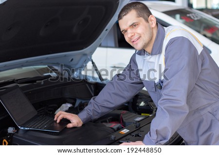 professional car mechanic working in auto repair service with laptop