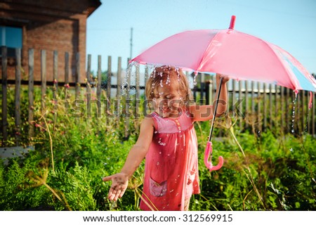 Little girl holding umbrella in the rain