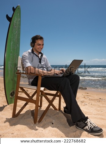 Vertical photographic image of young man with computer and surfboard on sunny beach in Australia