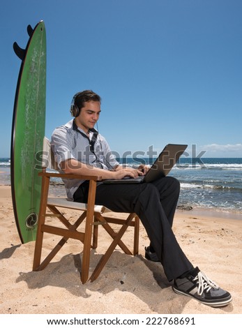 Vertical photographic image of young man with computer and surfboard on sunny beach in Australia