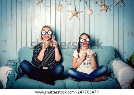 funny mom and daughter with false mustaches, playing at home