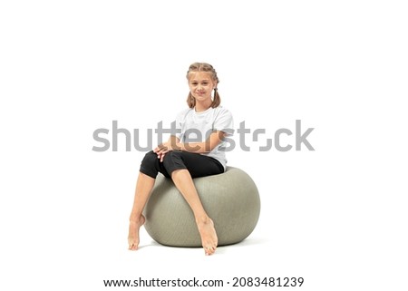Cute young girl sitting on fitness ball looking at the camera and smiling isolated on white background. Foto stock © 