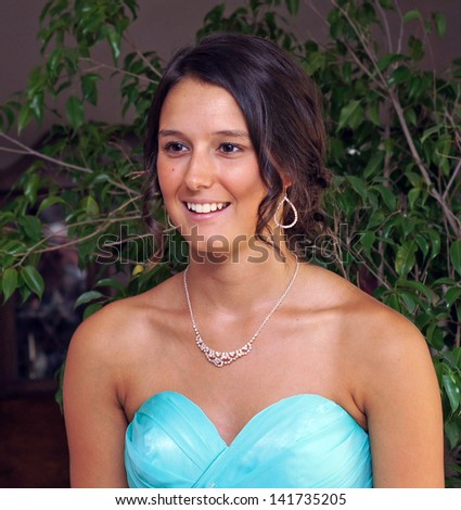 Beautiful young lady is dressed and ready for her prom, smiling and laughing in her gown