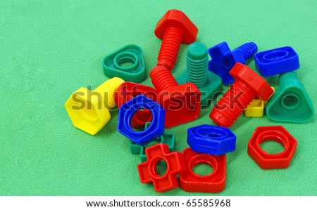 Colourful toy nuts and bolts on light green textured background