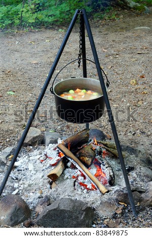 Stew cooks in a large kettle over an open fire