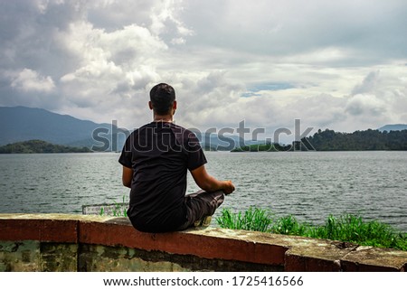 man meditating at pristine lake with mountain background image is taken at banasura sagar dam wayanad kerala india. the natural beauty of this place is amazing. Stock fotó © 